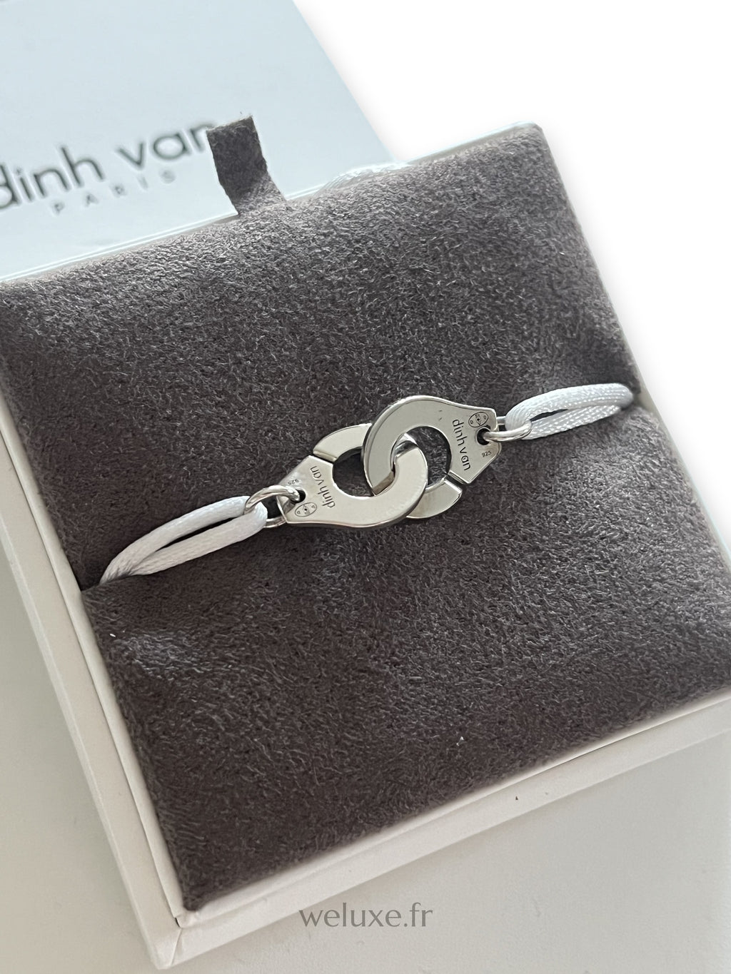 Bracelet Menottes R12 Dinh Van en argent sur cordon blanc, dans son écrin, vue rapprochée