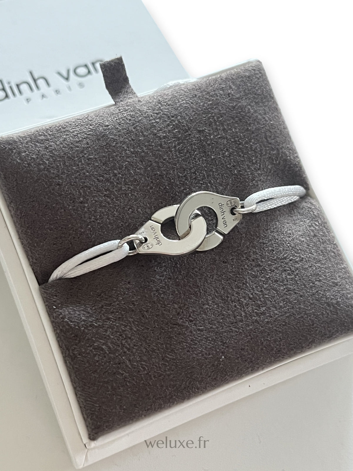 Bracelet Menottes R12 Dinh Van en argent sur cordon blanc, dans son écrin, vue rapprochée